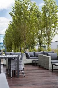 een patio met banken, tafels en bomen bij Holiday Inn Express - Lustenau in Lustenau