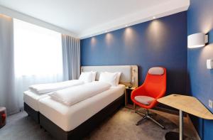a bedroom with a bed and a red chair at Holiday Inn Express - Lustenau in Lustenau