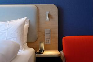 une chambre d'hôtel avec un lit et un fauteuil rouge dans l'établissement Holiday Inn Express - Lustenau, à Lustenau