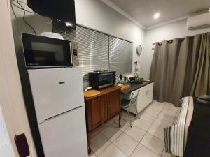 a kitchen with a refrigerator and a desk with a microwave at Delikaat Bed & Coffee in Prieska