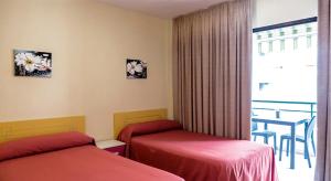 a hotel room with two beds and a balcony at Hostal Rosa in Villajoyosa
