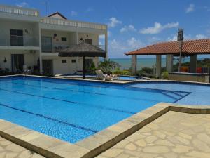 a large blue swimming pool in front of a building at Apartamento VISTA MAR - Condomínio Granito e Jasmim in Jacumã