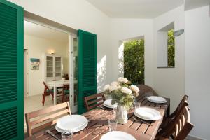 a dining room with a table and chairs and green shutters at Casina Simonetta by Mmega in Forte dei Marmi
