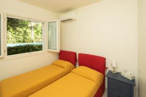 two beds in a room with a window at Casina Simonetta by Mmega in Forte dei Marmi +13 photos