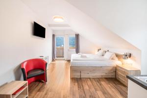 een slaapkamer met een bed en een rode stoel bij Mentenwirt Suite in Sankt Martin