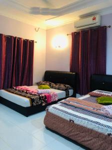 three beds in a room with red curtains at D'BERJAYA HOMESTAY & ROOMSTAY in Pantai Cenang