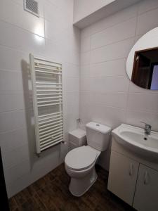 Baño blanco con aseo y lavamanos en Garsoniera Flamingo Garii 4 en Brasov