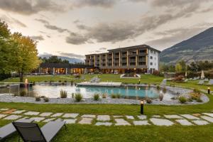 a resort with a pond in front of a building at Garden Park Hotel in Prato allo Stelvio