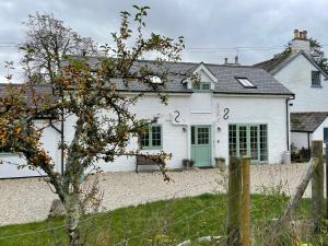 ein weißes Haus mit grüner Tür und einem Zaun in der Unterkunft Cottages at Woodlands, Appleloft in Wareham