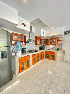 uma grande cozinha com armários de madeira e um frigorífico em MAHALO HOUSE B&B - Tu Casa Hospedaje en San Andrés Isla - em San Andrés