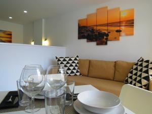 a dining table with wine glasses and a couch at Near the sea Las Arenas in Playa del Ingles