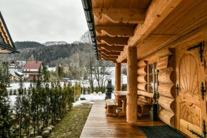 une véranda en bois d'une cabine avec vue sur une forêt enneigée dans l'établissement Domki 4 Seasons Zakopane, à Zakopane