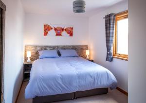 a bedroom with a bed and two paintings on the wall at Croftwood Cottage in Boat of Garten