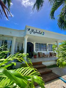 a white building with a porch with benches on it at MAHALO HOUSE B&B - Tu Casa Hospedaje en San Andrés Isla - in San Andrés