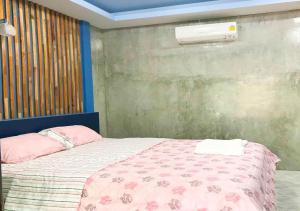 1 dormitorio con 1 cama con edredón rosa en ใสโพธิ์โฮมสเตย์, en Phatthalung