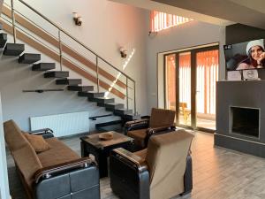 巴庫里阿尼的住宿－Villa Astoria Bakuriani，一间带两把椅子和楼梯的客厅