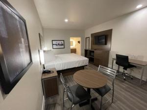 a hotel room with a bed and a table and chairs at Palace Inn Blue - Garth Rd in Baytown