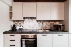 a kitchen with white cabinets and a sink and a stove at Lo Stallino by Quokka 360 - a stone's throw from the Hermann Hesse Museum in Montagnola