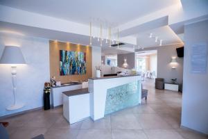 a lobby with a white counter and a painting on the wall at Hotel Baby in Rimini