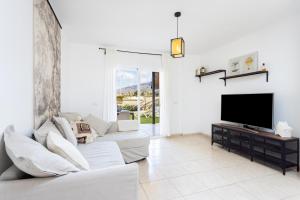 een witte woonkamer met een witte bank en een tv bij Nice Garden Valle del Sol in Adeje