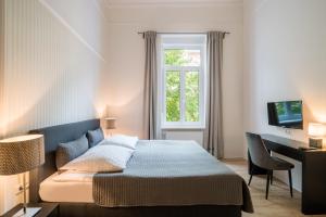 a bedroom with a bed and a desk and a window at Hotel Aurora in Wiesbaden