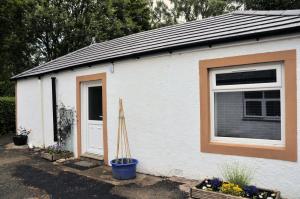 a white building with a window and a door at Arrochoile Cottage in Glasgow