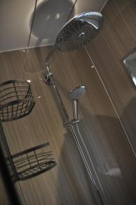 a shower with a shower head on top of a wooden floor at Arrochoile Cottage in Glasgow +4 photos