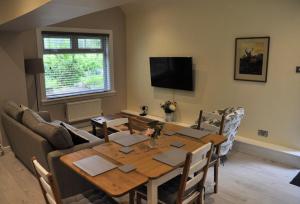 a living room with a dining room table and a television at Arrochoile Cottage in Glasgow