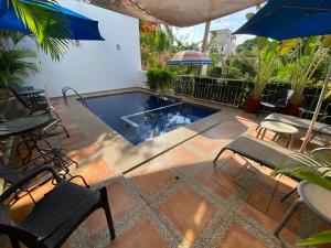 un patio con una piscina con sillas y sombrillas en Chacala Arrecifes 1 para 2 con Aire Acondicionado a solo 50 mts de la Playa ARF1, en Chacala