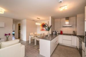 Una cocina y sala de estar con gabinetes blancos y una mesa. en Begonia, en Orihuela Costa