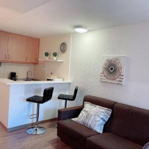 ein Wohnzimmer mit einem Sofa und 2 Stühlen sowie eine Küche in der Unterkunft Confortable Lake Placid in Pas de la Casa