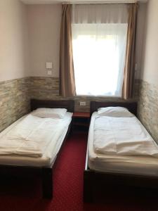 two twin beds in a room with a window at Mosoly Szallashely in Szeged