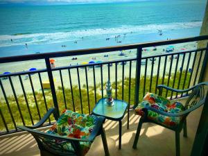 a balcony with two chairs and a table and a beach at Ocean Reef- Unique Oceanfront Condo-Free parking - Amazing pools in Myrtle Beach