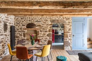 una sala da pranzo con parete in pietra, tavolo e sedie di LA PILOTINE - maison 2 chambres a Saint-Coulomb