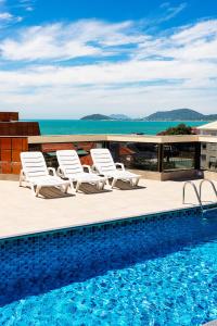 een zwembad met ligstoelen en de oceaan bij Ilhasul Hotel Residencia in Florianópolis