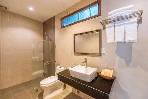 a bathroom with a sink and a toilet and a mirror at Qualia Resort Phu Quoc in Phú Quốc