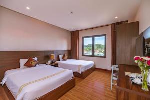 a hotel room with two beds and a window at Qualia Resort Phu Quoc in Phú Quốc