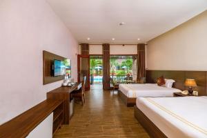 a hotel room with two beds and a desk at Qualia Resort Phu Quoc in Phú Quốc