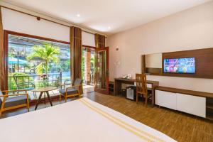 a bedroom with a bed and a desk and a table at Qualia Resort Phu Quoc in Phú Quốc
