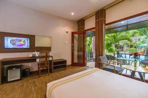 a hotel room with a bed and a tv and a table at Qualia Resort Phu Quoc in Phú Quốc