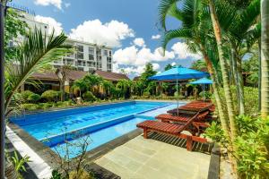 a swimming pool with benches and a blue umbrella at Qualia Resort Phu Quoc in Phú Quốc