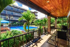 an outdoor balcony with a pool and palm trees at Qualia Resort Phu Quoc in Phú Quốc