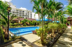 a resort swimming pool with palm trees and a building at Qualia Resort Phu Quoc in Phú Quốc