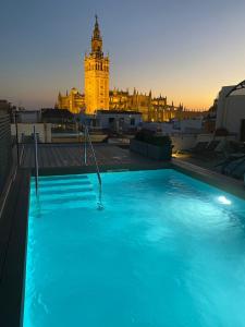 uma piscina no telhado de um edifício com uma torre de relógio em Joya del Casco Boutique Hotel by Shiadu em Sevilha
