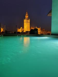 
a large clock tower towering over a city at night at Joya del Casco Boutique Hotel by Shiadu in Seville
