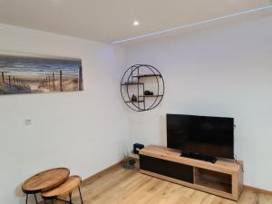 a living room with a flat screen tv and two chairs at Tedy style in De Haan