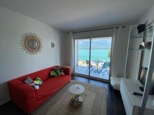 a living room with a red couch and a view of the ocean at Les Suites du Port in Le Bourget-du-Lac