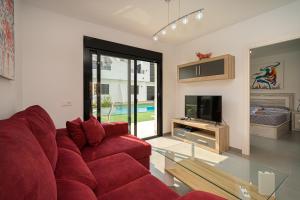 sala de estar con sofá rojo y TV en Flamingo Playa 7, en San Pedro del Pinatar