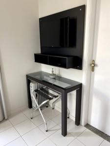 uma mesa preta com uma televisão na parede em Apartamento Studio - Novíssimo e Aconchegante em Caxambu MG em Caxambu