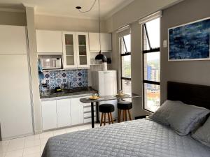 Cet appartement comprend une chambre avec un lit et une petite cuisine. dans l'établissement Apartamento Studio - Novíssimo e Aconchegante em Caxambu MG, à Caxambu